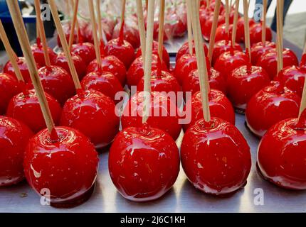 Süße glasierte rote Süßigkeitenäpfel auf Holzstäbchen zum Verkauf. Hochwertige Fotos Stockfoto