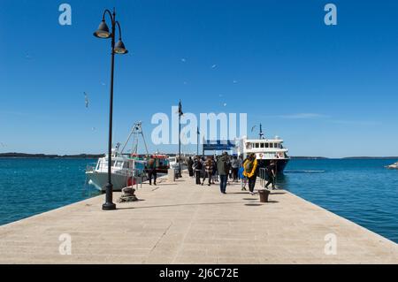 Fazana, Kroatien - 11. April 2022: Menschen warten auf der Anlegestelle für die Fähre zum Nationalpark Brijuni Inseln Stockfoto