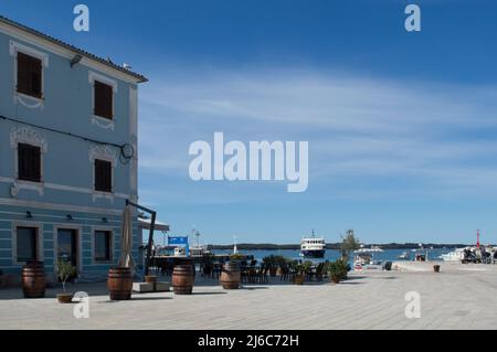 Fazana, Kroatien - 11. April 2022: Schöner Stadtplatz mit Terrassen, Abfahrtshafen für den Bootstransfer zum Nationalpark Brijuni Inseln Stockfoto