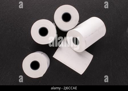 Mehrere Rollen Papierband für eine Kasse auf einem Schieferstein, Makro, Draufsicht. Stockfoto