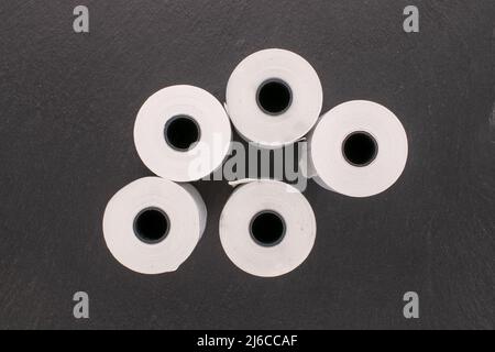 Mehrere Rollen Papierband für eine Kasse auf einem Schieferstein, Makro, Draufsicht. Stockfoto