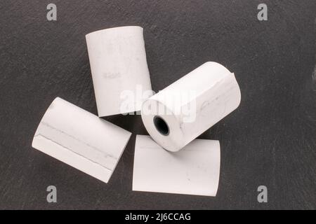 Mehrere Rollen Papierband für eine Kasse auf einem Schieferstein, Makro, Draufsicht. Stockfoto