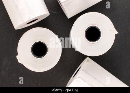 Mehrere Rollen Papierband für eine Kasse auf einem Schieferstein, Makro, Draufsicht. Stockfoto