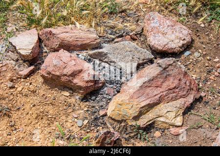 Blick von oben auf das erloschene Lagerfeuer in der bergigen Gegend. Stockfoto