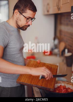 Mann bereitet hausgemachte Tomatensauce für Pizza oder Pasta. Glücklich zufrieden männlichen Vorbereitung vegetarische Snacks, Essen zum Abendessen oder Party, genießen Freizeit, Hobby. Stockfoto