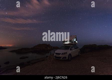 Vanlife Camping am Meer - Van mit Dachzelt am Ufer einer Bucht an der Westküste Sardiniens unter dem strahlenden Sternenhimmel, Italien, Europa Stockfoto