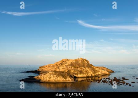 Sardischer Charme - zwei Zirruswolken über einer felsigen Insel in der Bucht von Torre Argentario an der Westküste in der Morgensonne, Sardinien, Italien, Europa Stockfoto