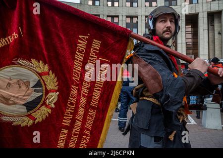 Moskau, Russland. 30.. April 2022.Ein Mann mit sowjetischer Flagge geht eine Sacharova-Allee in Moskau, Russland, entlang Stockfoto