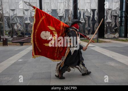 Moskau, Russland. 30.. April 2022.Ein Mann mit sowjetischer Flagge geht eine Straße im Chodynskoye Pole Park in Moskau, Russland, entlang Stockfoto