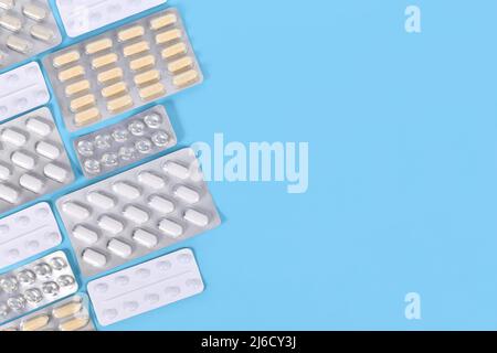 Kapseln und Pillen in Blisterpackungen auf der Seite des blauen Hintergrunds mit Platz für Kopien Stockfoto