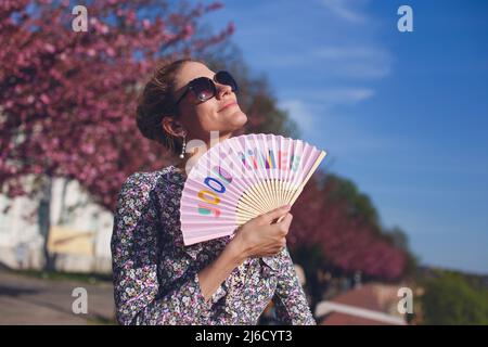 Nostalgische Frau hält gute Zeiten Handfächer im Sonnenuntergang im Frühling Stockfoto