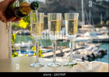 Drei Gläser französischen Champagner-Sekt und Blick auf bunte Fischerboote im alten Hafen von Cassis, Provence, Frankreich, Sommer Stockfoto