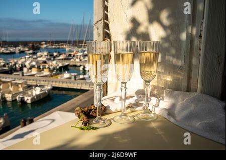 Drei Gläser französischer Champagner Sekt und Blick auf bunte Fischerboote im alten Hafen von Cassis, Provence, Frankreich, Sommerfest in PR Stockfoto