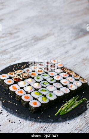 Sushi-Rolle mit Lachs, Thunfisch, Avocado und Gurke. Traditionelles japanisches Essen. Eine Menge Maki. Sushi-Brötchen. Draufsicht Stockfoto