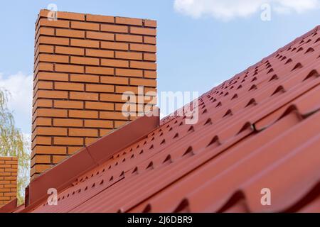 Dachziegel aus rotem Metall und Kamin Stockfoto