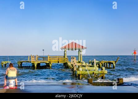 Eine Frau fischt in der Nähe eines vom Sturm beschädigten Piers in der Gulfport Municipal Marina am 24. April 2022 in Gulfport, Mississippi. Stockfoto