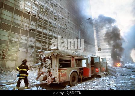 New York City Feuerwehrmann zieht Wasserschlauch von Feuerwehrauto inmitten von Trümmern und brennenden Gebäuden nach dem Terroranschlag am 11.. September auf das World Trade Center, New York City, New York, USA, Unidentified Artist Stockfoto