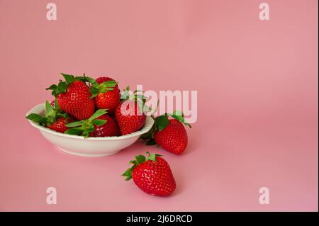 Erdbeeren in einer weißen Schüssel auf rosa Hintergrund Stockfoto
