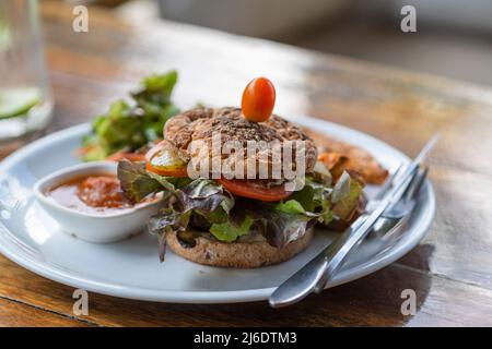 Vegetarischer Burger mit Falafel und Gemüsesalat, Tomaten, Champignon und Tofu-Käse auf Teller mit Süßkartoffeln, Nahaufnahme Stockfoto