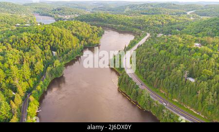 Luftaufnahme des Gatineau Flusses in der Nähe des Dorfes Wakefield, Kanada. Wolken, die sich im Flusswasser spiegeln, schlängelt sich eine Straße mit Autos entlang des Kurses Stockfoto