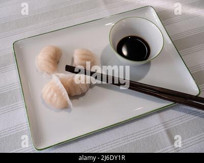 Dim Sum oder Har Gow Shrimp Dumpling mit Essstäbchen und Sojasauce, auch als ha-Gow, Heukau oder Hakao anglizisiert Stockfoto