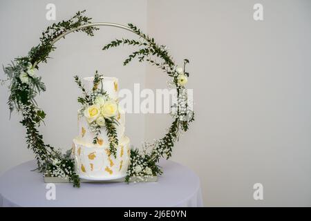 Dreistufiger Hochzeitstorte mit Blattgold und frischen Blumen Stockfoto
