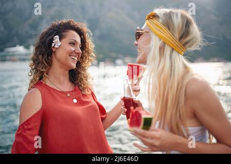 Freundinnen lachen und kleine Gespräche auf See führen. Zweisamkeit, Urlaub, Freundschaft, Lifestyle-Konzept. Stockfoto