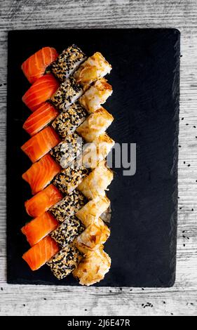 Sushi Set Nigiri und Sushi-Rollen auf schwarzem Stein Schieferteller Board. Platz für tex. instagram Geschichten Stockfoto
