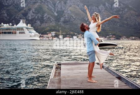 Verliebte Paare. Frau in weißem Kleid wird von ihrem Mann gehalten und fühlt Liebe, Freude und Freiheit. Hochzeit, Flitterwochen, Liebeskonzept Stockfoto