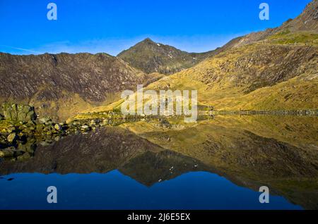 Die Ruinen der alten Zerkleinerungsmühle spiegeln sich in Llyn Llydaw auf dem Miner's Track in Mt Snowdon, Wales, Großbritannien Stockfoto