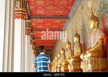 Besucher im Kloster mit einer großen Gruppe sitzender Buddha-Bilder im Wat Arun oder im Tempel der Morgenröte, Bangkok, Thailand Stockfoto