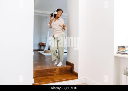 Junge schwarze Frau tanzt und lächelt, während sie zu Hause Musik hört Stockfoto
