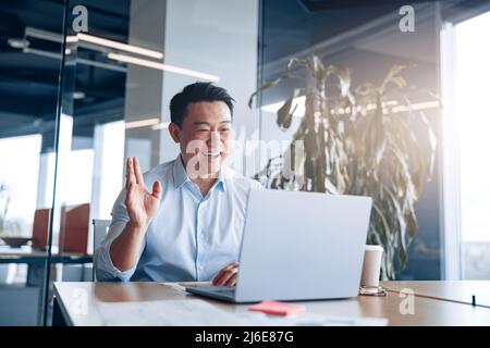 Positiver asiatischer Geschäftsmann, der in Videoanrufen mit einem Geschäftspartner kommuniziert Stockfoto