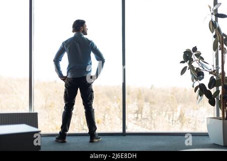 Porträt eines selbstbewussten Geschäftsmanns, der durch das Fenster schaut Stockfoto