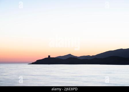 Romantische Landschaft - Abenddämmerung am Meer nach Sonnenuntergang in der Bucht von S'Abba Druche an der Westküste Sardiniens mit Blick auf den Turm am Kap Torre Argentina Stockfoto