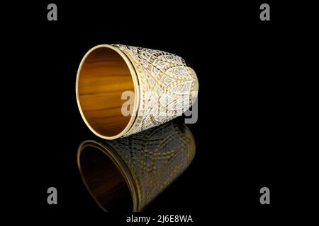 Kleines Golden White Antik Vintage Messing Schnapsglas vergoldet auf schwarzem Hintergrund. Metall Weinbecher Kelch mit Schnitzerei Gravur Muster. Stockfoto