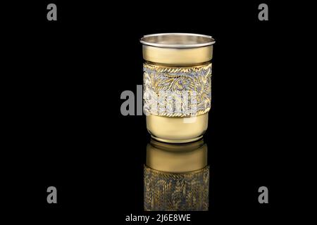 Kleines Golden White Antik Vintage Messing Schnapsglas vergoldet auf schwarzem Hintergrund. Metall Weinbecher Kelch mit Schnitzerei Gravur Muster. Stockfoto