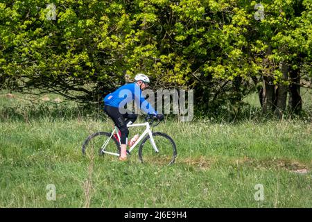 Sportradler, die auf einer Steinspur in der grünen Frühlingslandschaft reiten Stockfoto