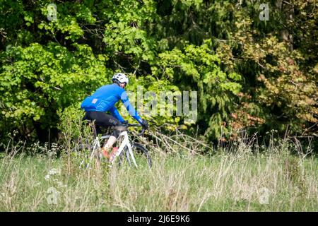 Sportradler, die auf einer Steinspur in der grünen Frühlingslandschaft reiten Stockfoto