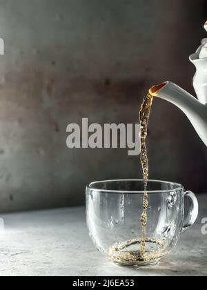 Tee wird mit Dampf in eine Teetasse aus Glas gegossen Stockfoto