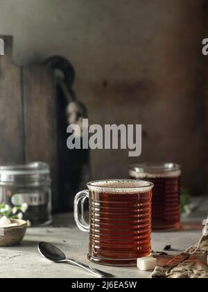Stillleben gemütliche Komposition mit zwei Glaskrügen schwarzen Tee auf texturiertem Hintergrund Stockfoto