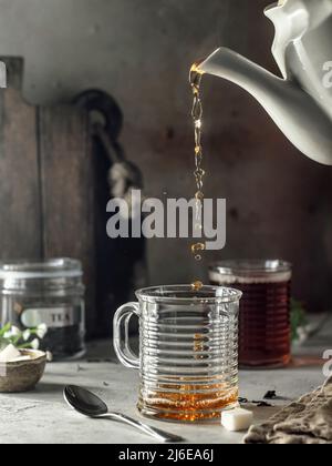 Stillleben mit schwarzem Tee in Glas gegossen. Mit Dampf. Bereiten Sie Tee zu. Selektiver Fokus Stockfoto