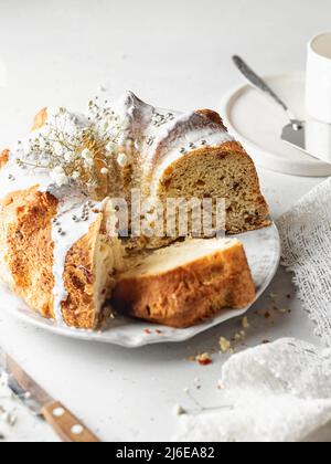 Geschnittener Bundt-Kuchen mit Puderstreuseln und Blumen dekoriert. High Key Stillleben Zusammensetzung Stockfoto