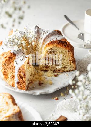 Bundt-Kuchen mit Puderstreuseln und Blumen dekoriert. High-Key mit einem Rahmen von Blumen in Unschärfe Stockfoto