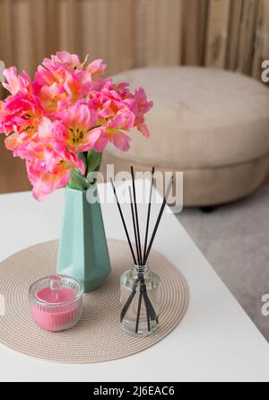 Duftrohrdiffusor, Blumen in Vase und Kerze auf dem Tisch Stockfoto