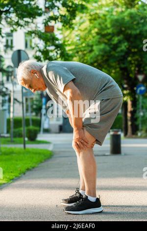 Älterer Mann, der während seines Jogging-Trainings an Knieschmerzen litt Stockfoto