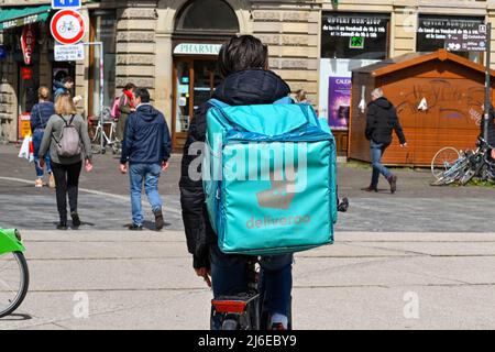 Straßburg, Frankreich - April 2022: Lieferperson mit Rucksäcken für Deliveroo auf einer Straße im Stadtzentrum von Straßburg Stockfoto