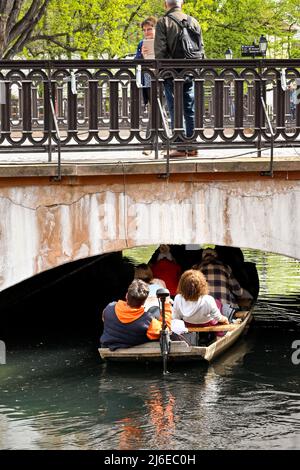 Colmar, Frankreich - 2022. April: Touristen in einem Boot auf dem Kanal, der durch die Stadt läuft senken ihren Kopf und Körper, um eine sehr niedrige Brücke zu vermeiden Stockfoto