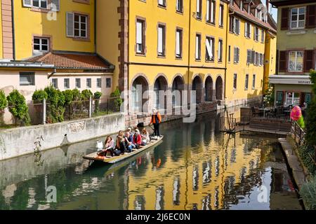 Colmar, Frankreich - April 2022: Touristen auf einem kleinen Boot auf dem Kanal, der durch die Stadt läuft Stockfoto