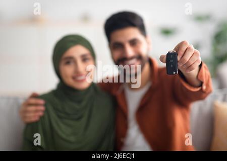 Glückliches Nahöstliches Paar, Das Automobilschlüssel Zur Kamera Im Innen Zeigt Stockfoto
